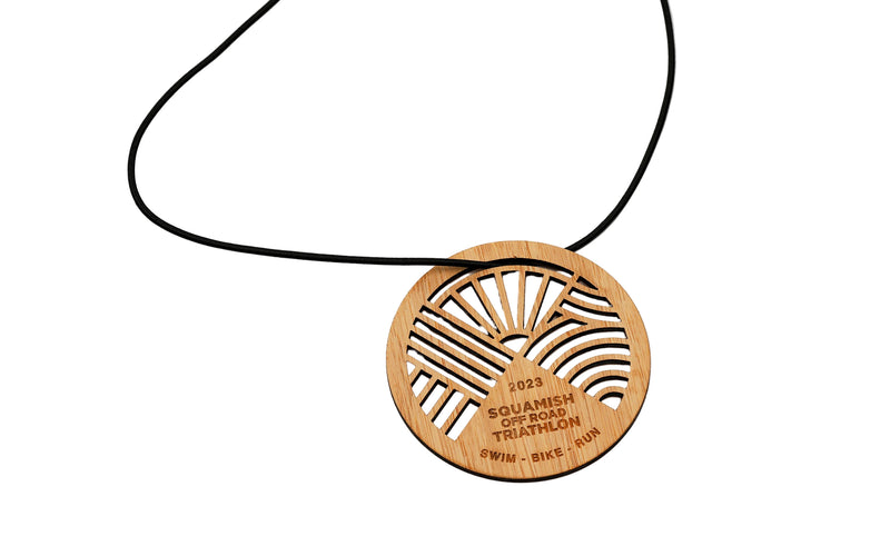 Wooden pendant with engraved design on a black cord against a white background