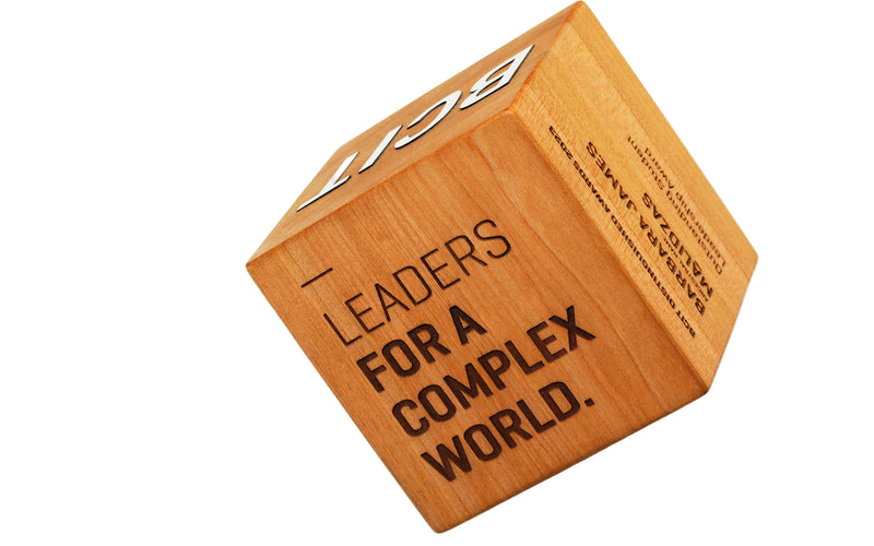 Wooden block with 'Leaders for a Complex World' text on a white background