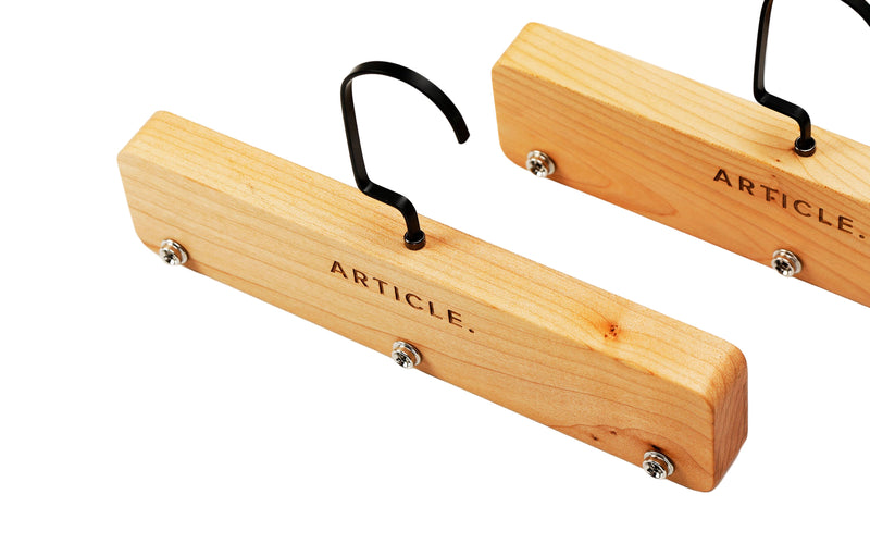 Wooden hangers with black hooks on a white background, branded 'Article'.